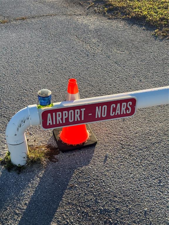 A white gate arm with a red sign reading "AIRPORT - NO CARS" and a traffic cone — 11500 PILOT COUNTRY DRIVE, SPRING HILL, FL