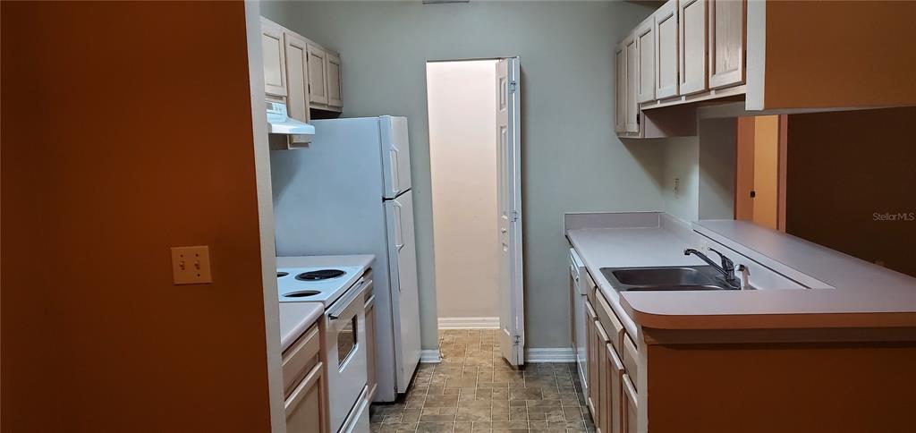 A kitchen features white appliances, light-colored wooden cabinets, and a pass-through window — 5620 PINNACLE HEIGHTS CIRCLE UNIT 304, TAMPA, FL