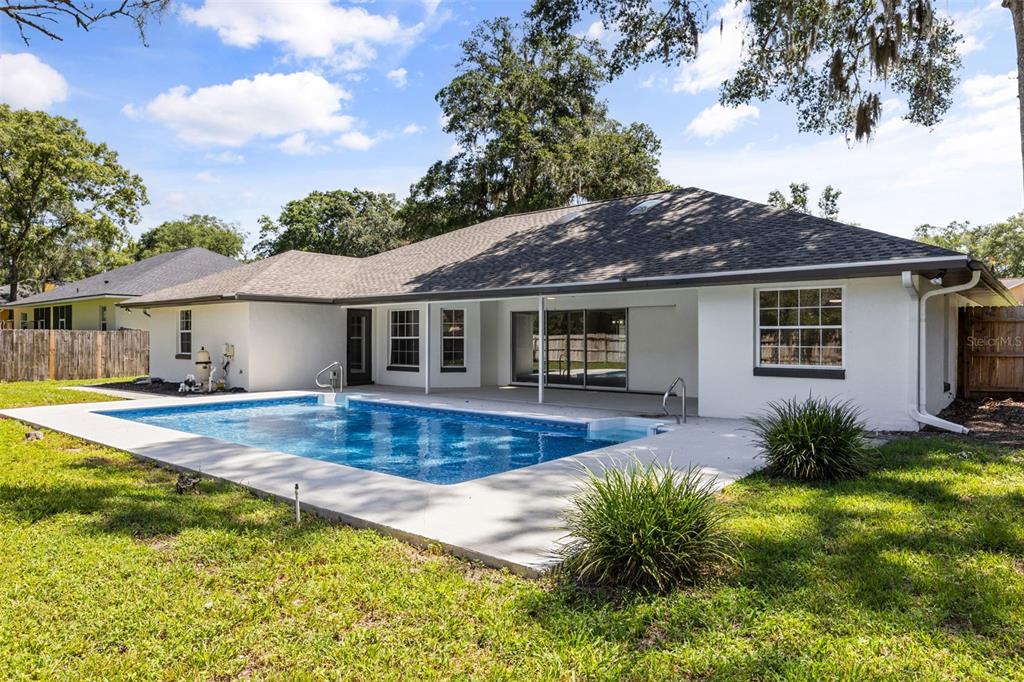 A white house with a rectangular swimming pool and a concrete patio in the backyard — 3690 SE 56TH TERRACE, OCALA, FL