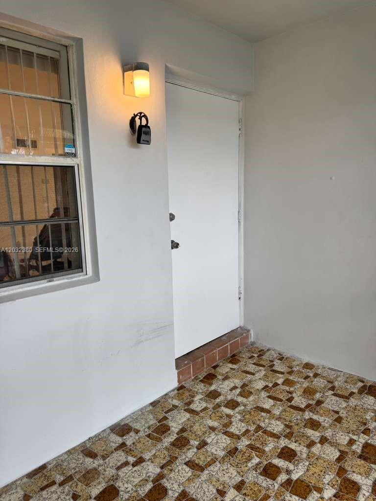 A white door and a window with security bars open onto a tiled porch — 705 NE 2nd St # 11, Hallandale Beach FL 33009, HALLANDALE BEACH, FL