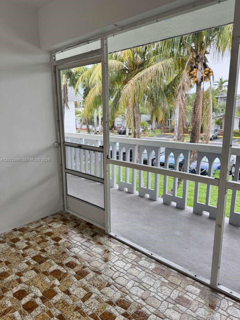 A screened-in balcony with tiled flooring overlooks a parking area with palm trees — 705 NE 2nd St # 11, Hallandale Beach FL 33009, HALLANDALE BEACH, FL