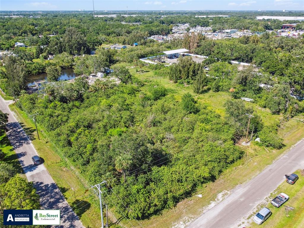 An aerial view shows a large, undeveloped, tree-covered lot situated between two paved roads — 4713 EL CAMINO BLANCO BOULEVARD, TAMPA, FL
