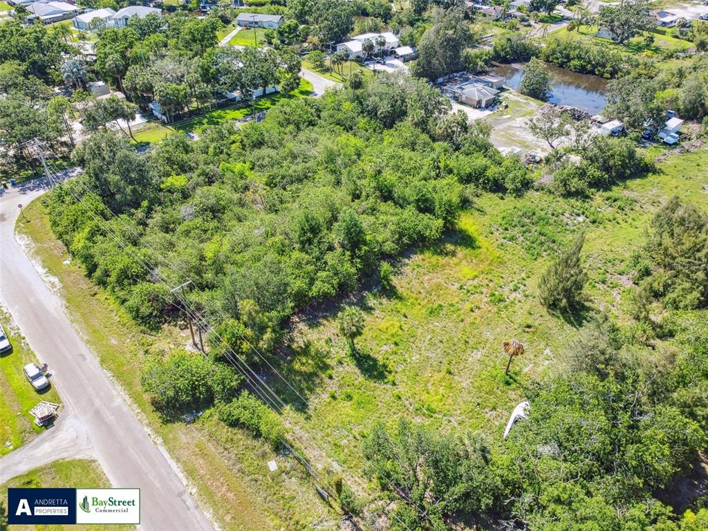 An aerial view shows a vacant, partially wooded lot adjacent to a paved road — 4713 EL CAMINO BLANCO BOULEVARD, TAMPA, FL