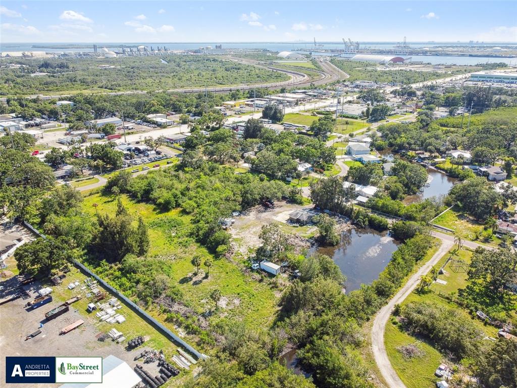 An aerial view shows a vacant lot with a pond, trees, and nearby industrial buildings — 4713 EL CAMINO BLANCO BOULEVARD, TAMPA, FL