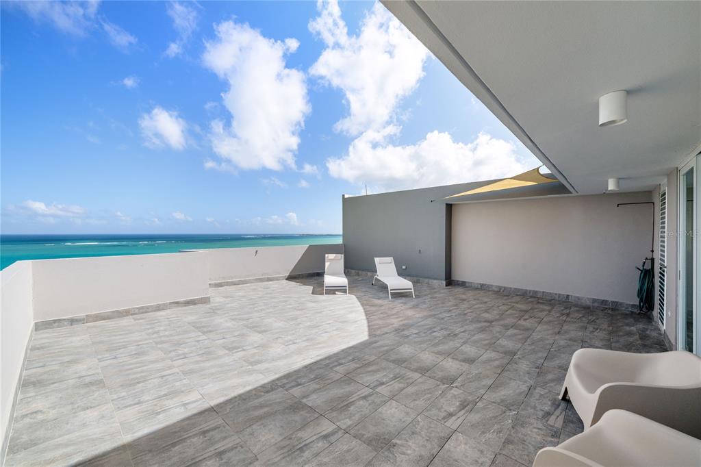 A spacious outdoor terrace features gray tile flooring, two lounge chairs, and ocean views — 4123 ISLA VERDE AVE, WALDORF TOWER UNIT PH-4, CAROLINA, PR
