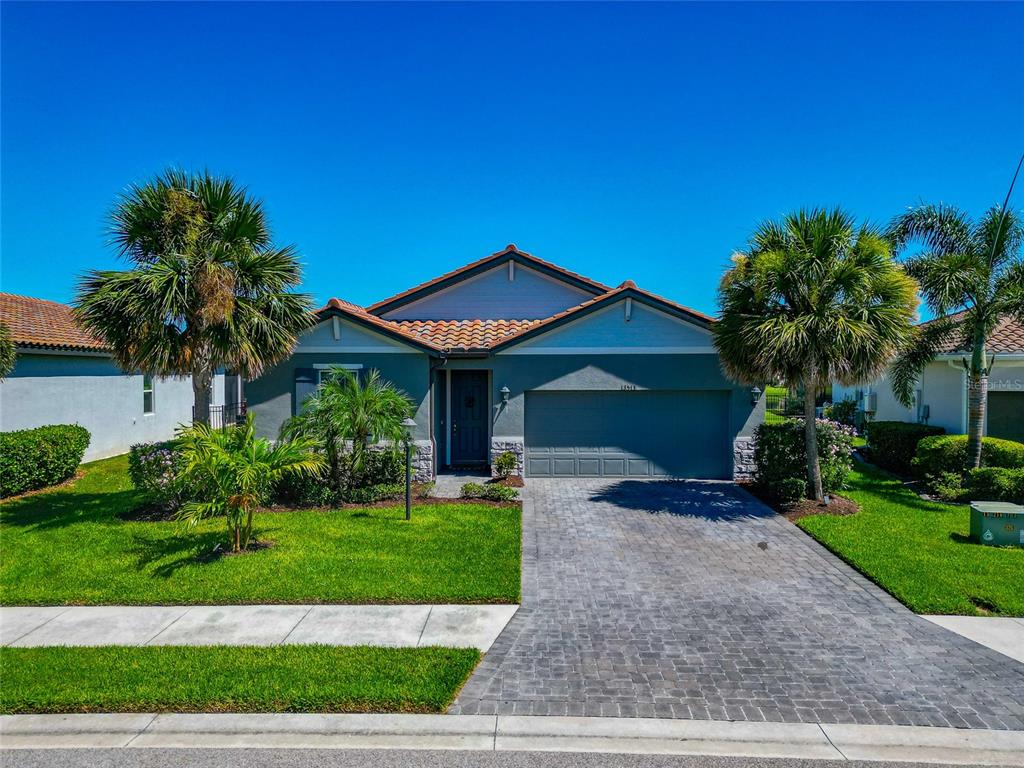 A single-story house with a blue exterior, a tiled roof, and a paved driveway — 13513 FLAT WOODS TERRACE, BRADENTON, FL