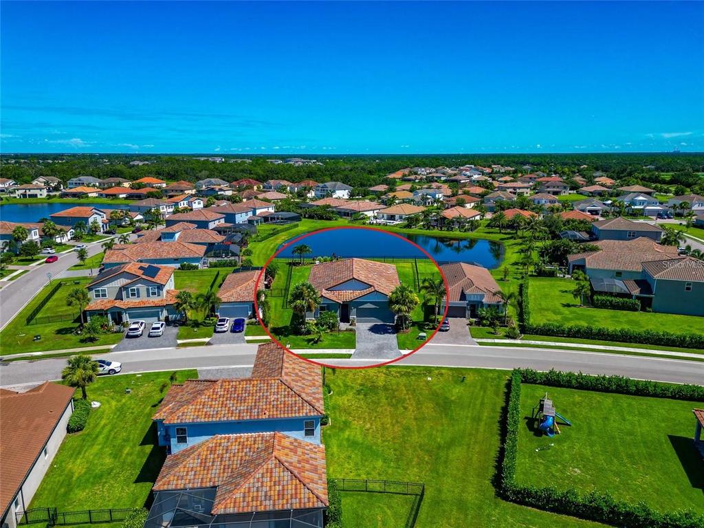 An aerial view shows a single-story house with a tiled roof and a backyard pond — 13513 FLAT WOODS TERRACE, BRADENTON, FL