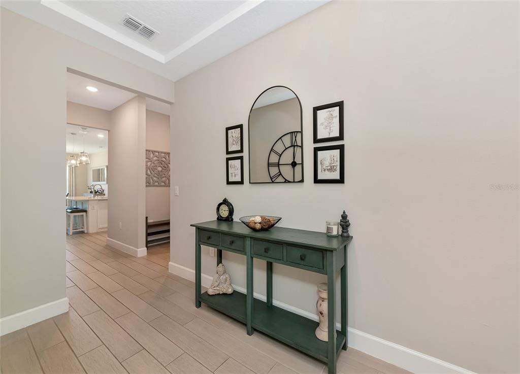 A teal console table sits against a beige wall in a tiled entryway — 13513 FLAT WOODS TERRACE, BRADENTON, FL