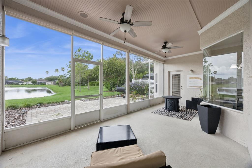 A screened-in patio features a beige concrete floor, two ceiling fans, and a lake view — 316 HAZELTINE DRIVE, DEBARY, FL