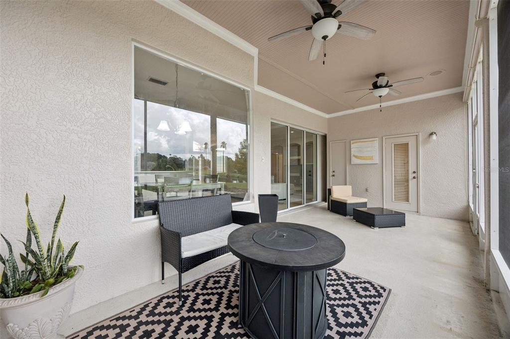 A covered patio features a fire pit, outdoor seating, ceiling fans, and a large window — 316 HAZELTINE DRIVE, DEBARY, FL