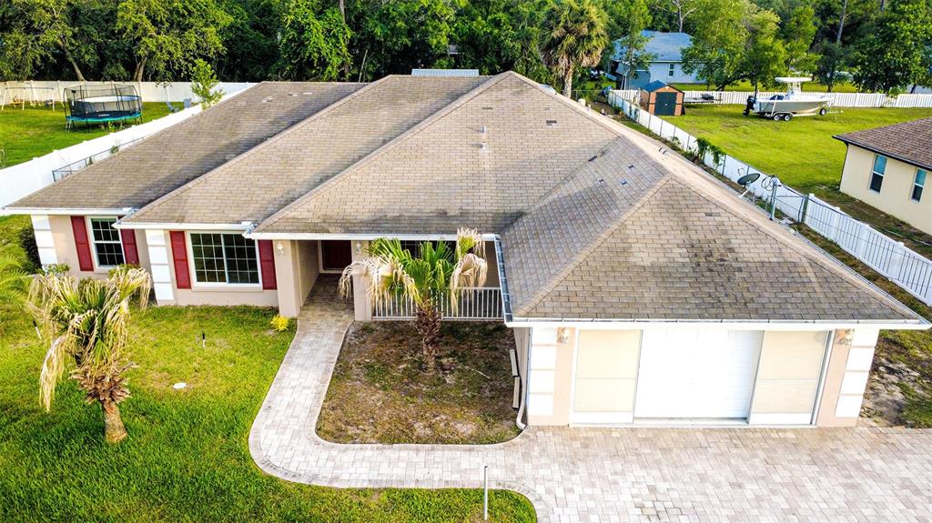 An aerial view shows a single-story house with a shingled roof and a paved driveway — 12036 PENGUIN AVENUE, WEEKI WACHEE, FL