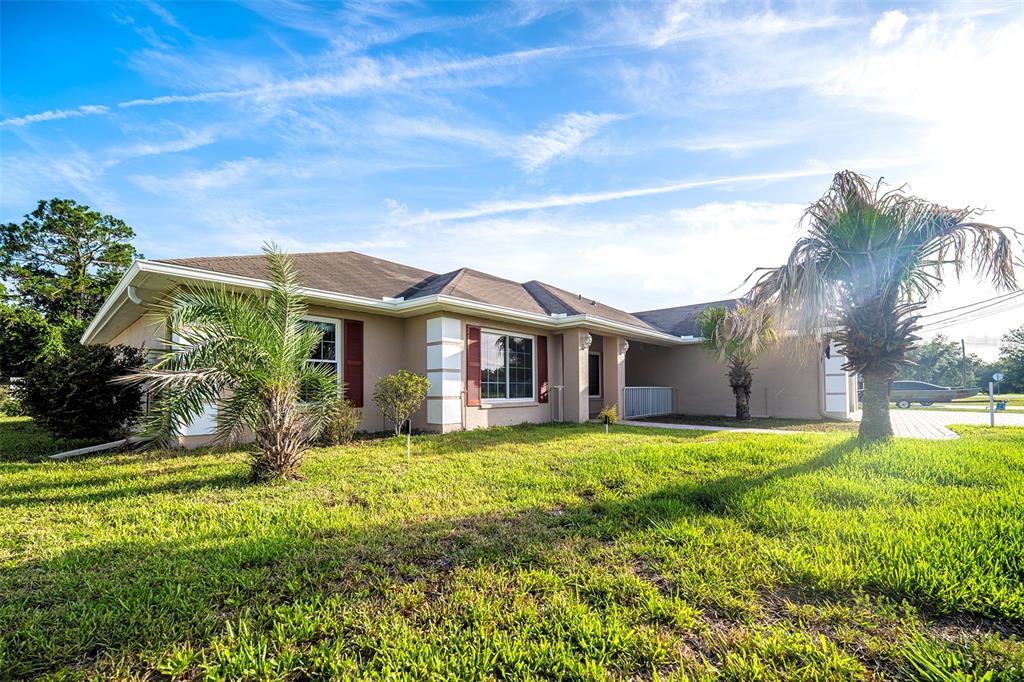 A single-story tan house with a brown roof, red shutters, and palm trees in front — 12036 PENGUIN AVENUE, WEEKI WACHEE, FL
