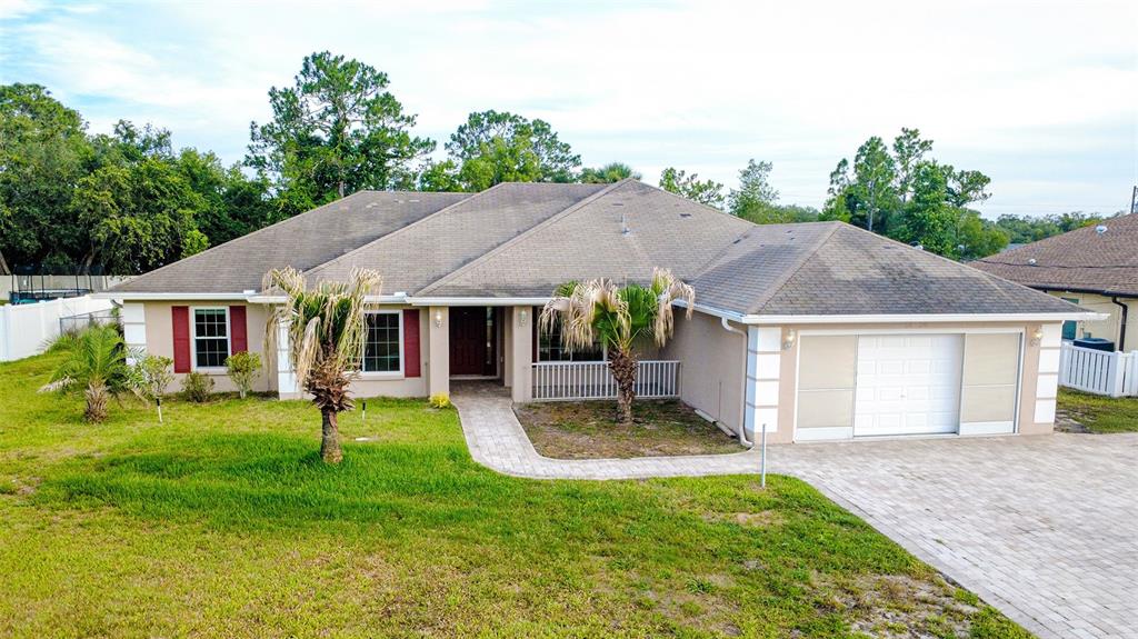 A single-story house with a beige exterior, red shutters, a paved driveway, and two palm trees — 12036 PENGUIN AVENUE, WEEKI WACHEE, FL