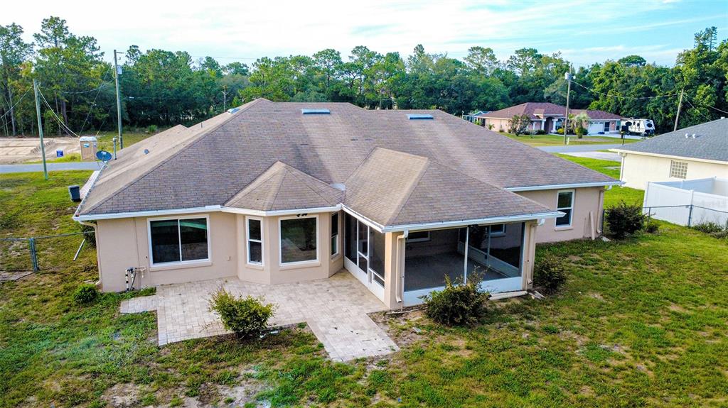 An aerial view of a tan house with a shingled roof, patio, and screened-in porch — 12036 PENGUIN AVENUE, WEEKI WACHEE, FL