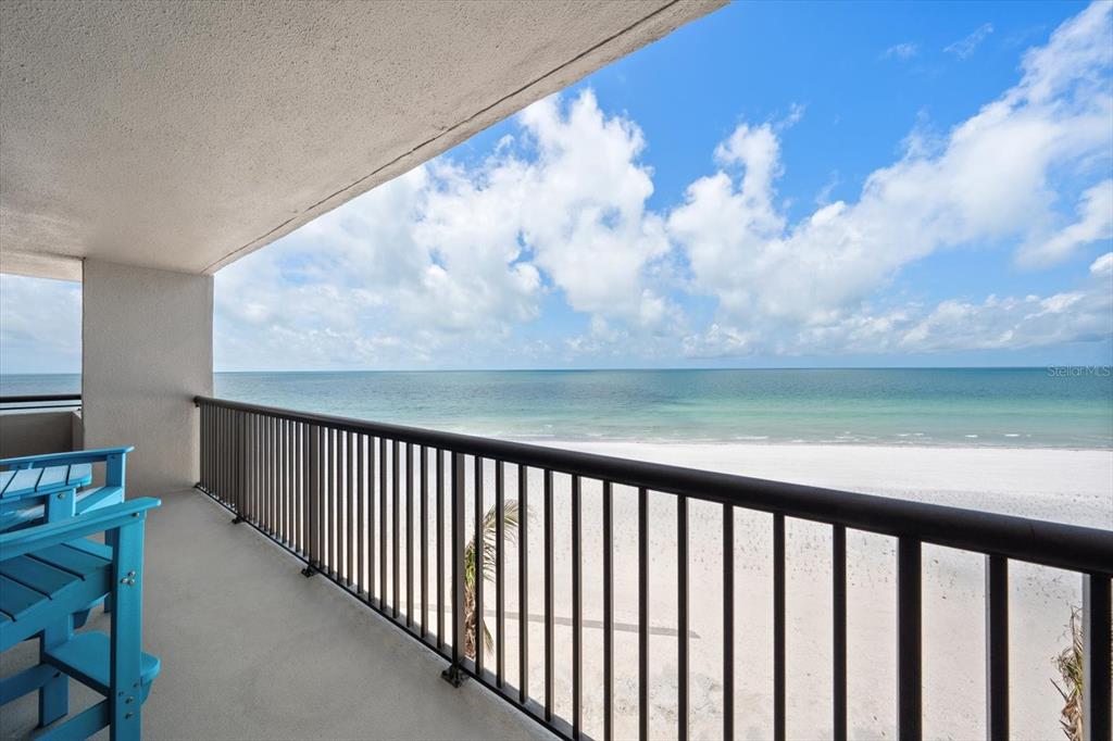 A balcony with blue chairs overlooks a sandy beach and the ocean — 1660 GULF BOULEVARD UNIT 403, CLEARWATER BEACH, FL