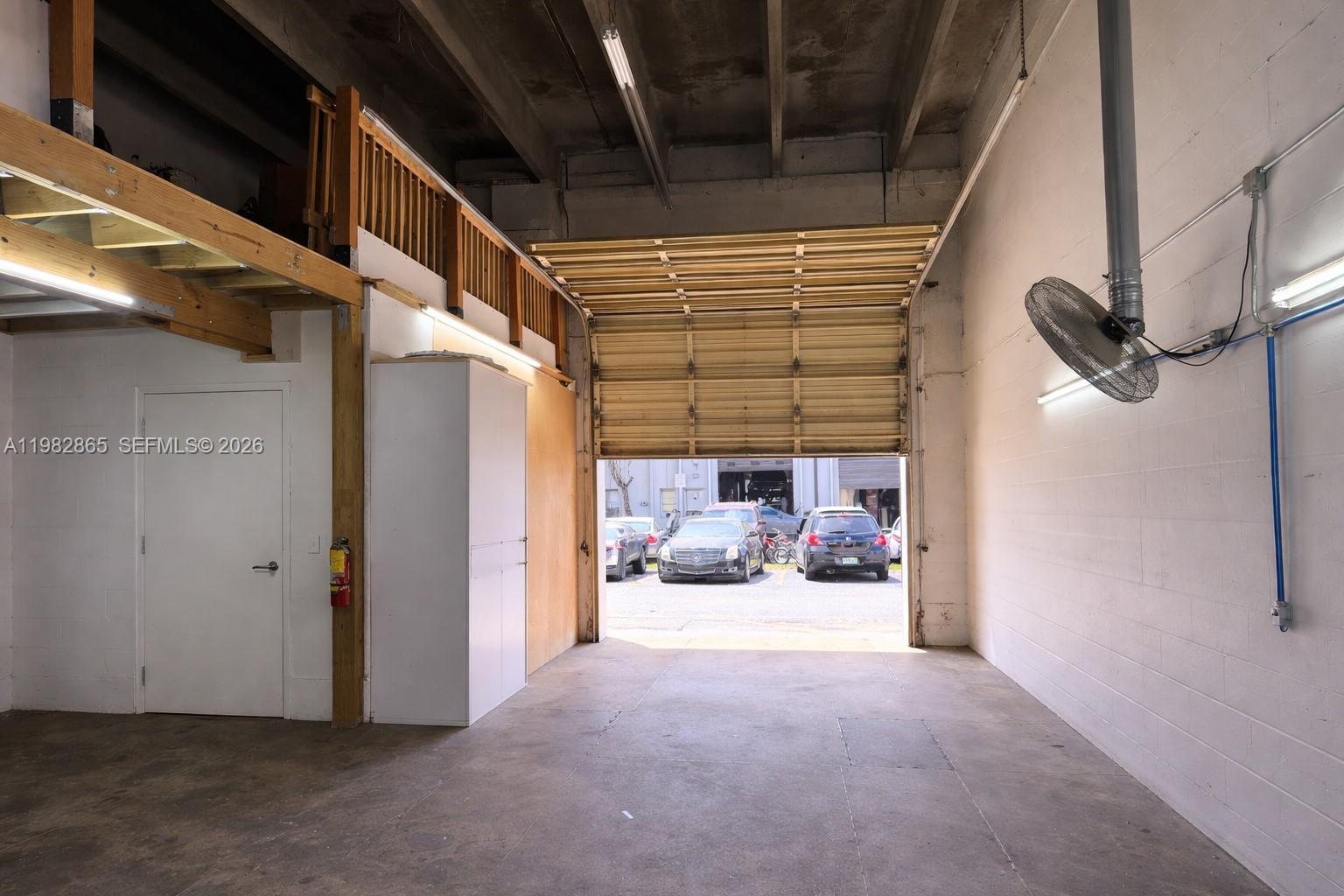 An industrial warehouse space features a roll-up door, a mezzanine level, and concrete flooring — 2016 NW 55th Ave, Margate FL 33063, MARGATE, FL
