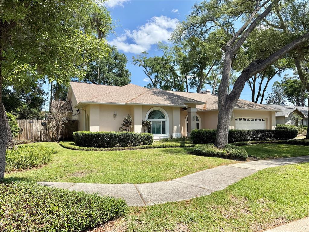A single-story house with a beige exterior, a two-car garage, and a manicured lawn — 6326 N QUEENSWAY DR, TEMPLE TERRACE, FL