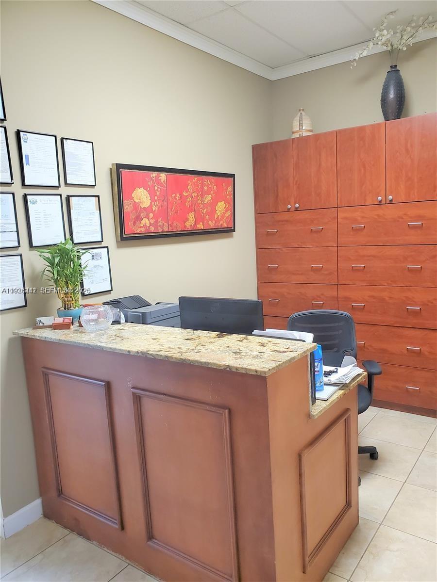 A reception area features a granite-topped desk, wood cabinetry, and framed documents on the wall — 2751 Executive Park Dr # 202, Weston FL 33331, WESTON, FL