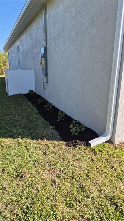 A side view of a house exterior shows a landscaped garden bed with small plants — 122 NAOMI PL, ROTONDA WEST, FL