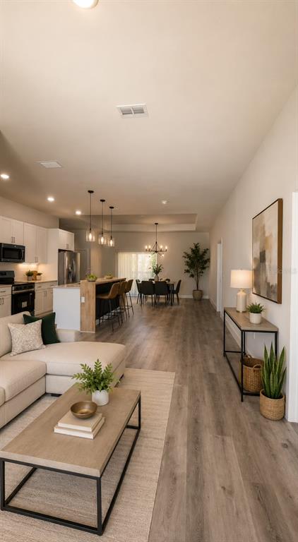 An open-concept living room and kitchen feature light wood flooring and modern neutral decor — 122 NAOMI PL, ROTONDA WEST, FL