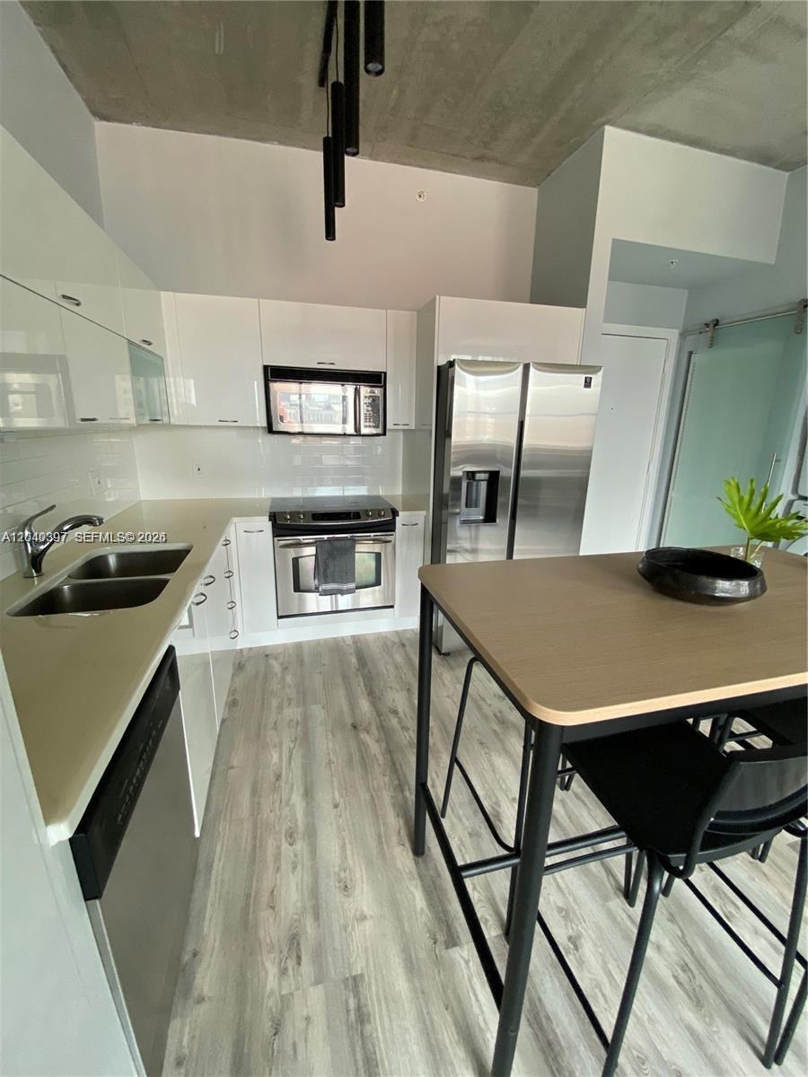A modern kitchen features white cabinets, stainless steel appliances, and a wood-topped island — 133 NE 2nd Ave # 915, Miami FL 33132, MIAMI, FL