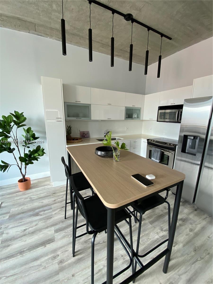 A modern kitchen features white cabinetry, stainless steel appliances, and a wooden island with stools — 133 NE 2nd Ave # 915, Miami FL 33132, MIAMI, FL