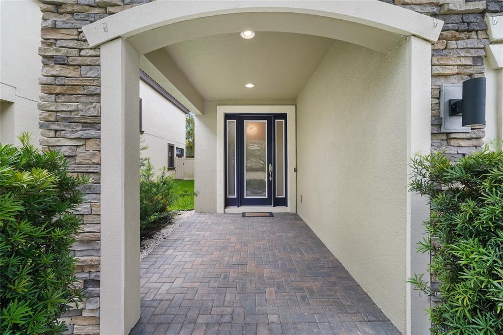 A covered entryway features a paved walkway leading to a dark blue front door — 13000 BURNS DRIVE, ODESSA, FL