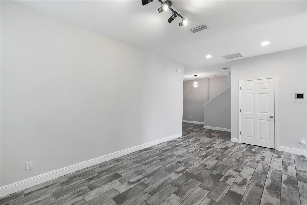 A room with light gray walls, gray wood-look tile flooring, and a track lighting fixture — 13000 BURNS DRIVE, ODESSA, FL