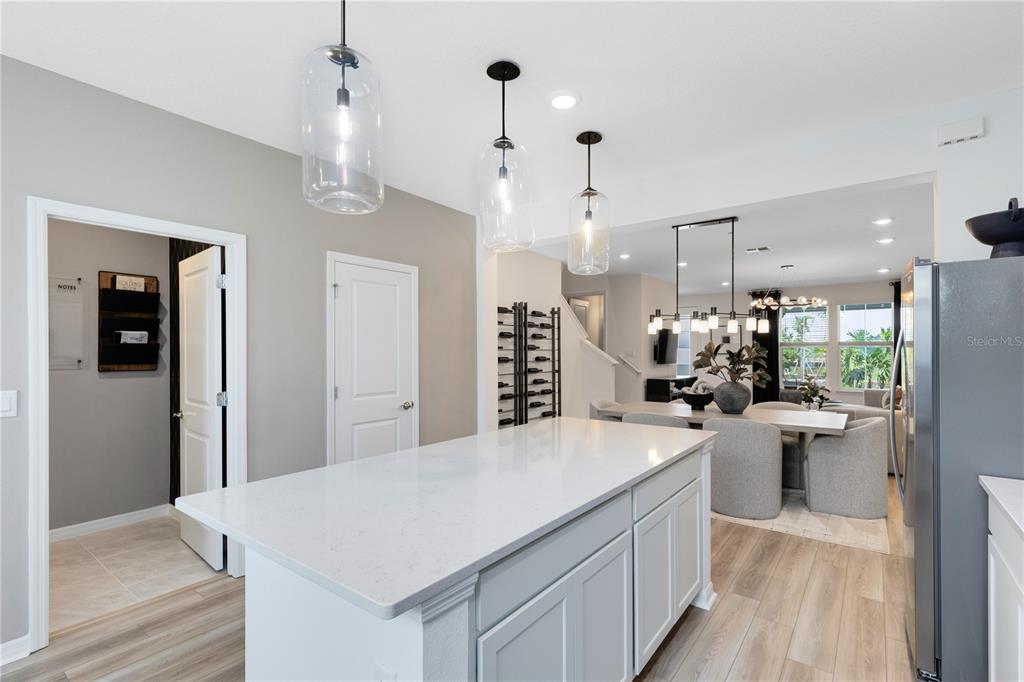 A kitchen island with white quartz countertops sits before a dining area and living room — 4580 ORCHARD VIEW ALLEY, CLERMONT, FL