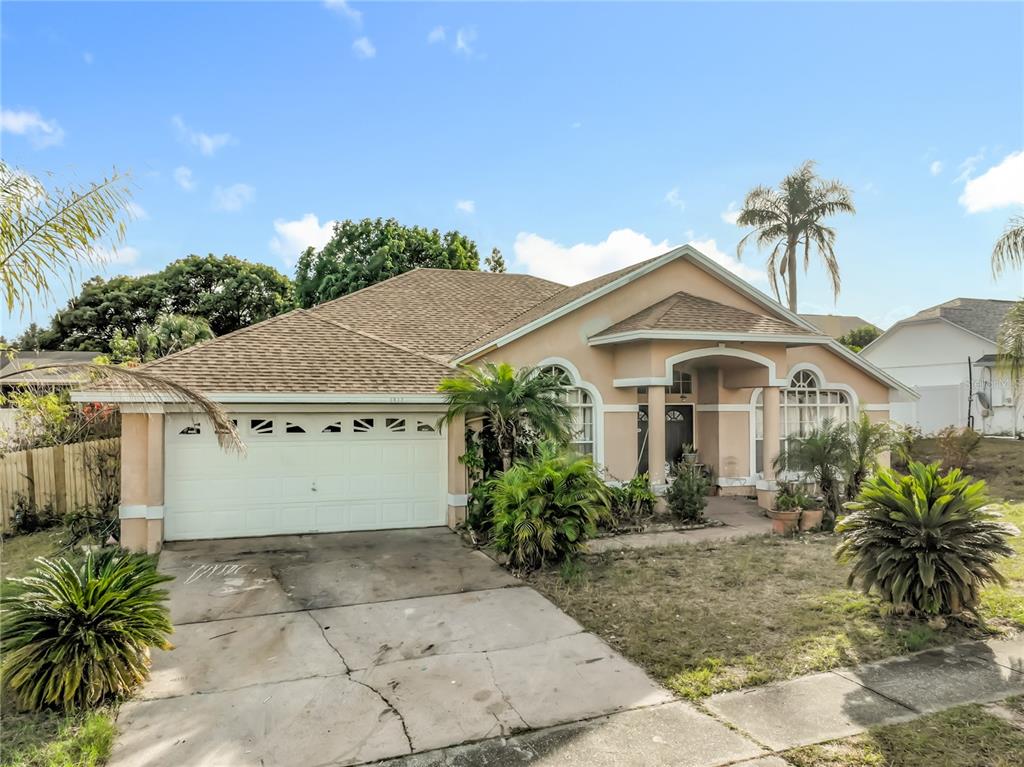 A single-story house with a tan stucco exterior, a two-car garage, and a palm tree — 6832 GOLDENEYE DRIVE, ORLANDO, FL