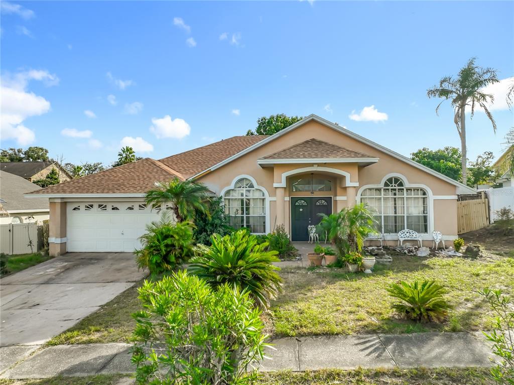 A single-story house with a tan stucco exterior, a two-car garage, and a palm tree — 6832 GOLDENEYE DRIVE, ORLANDO, FL
