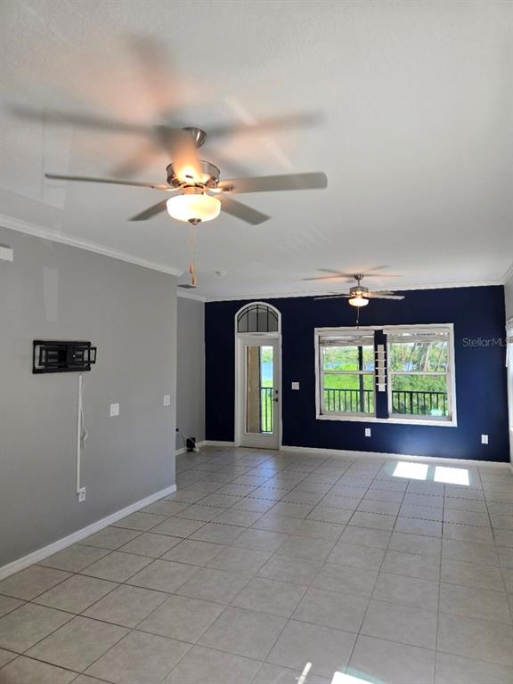 A kitchen island with a granite countertop overlooks a tiled living area with ceiling fans — 4640 WILLET COOPER COURT, TAMPA, FL