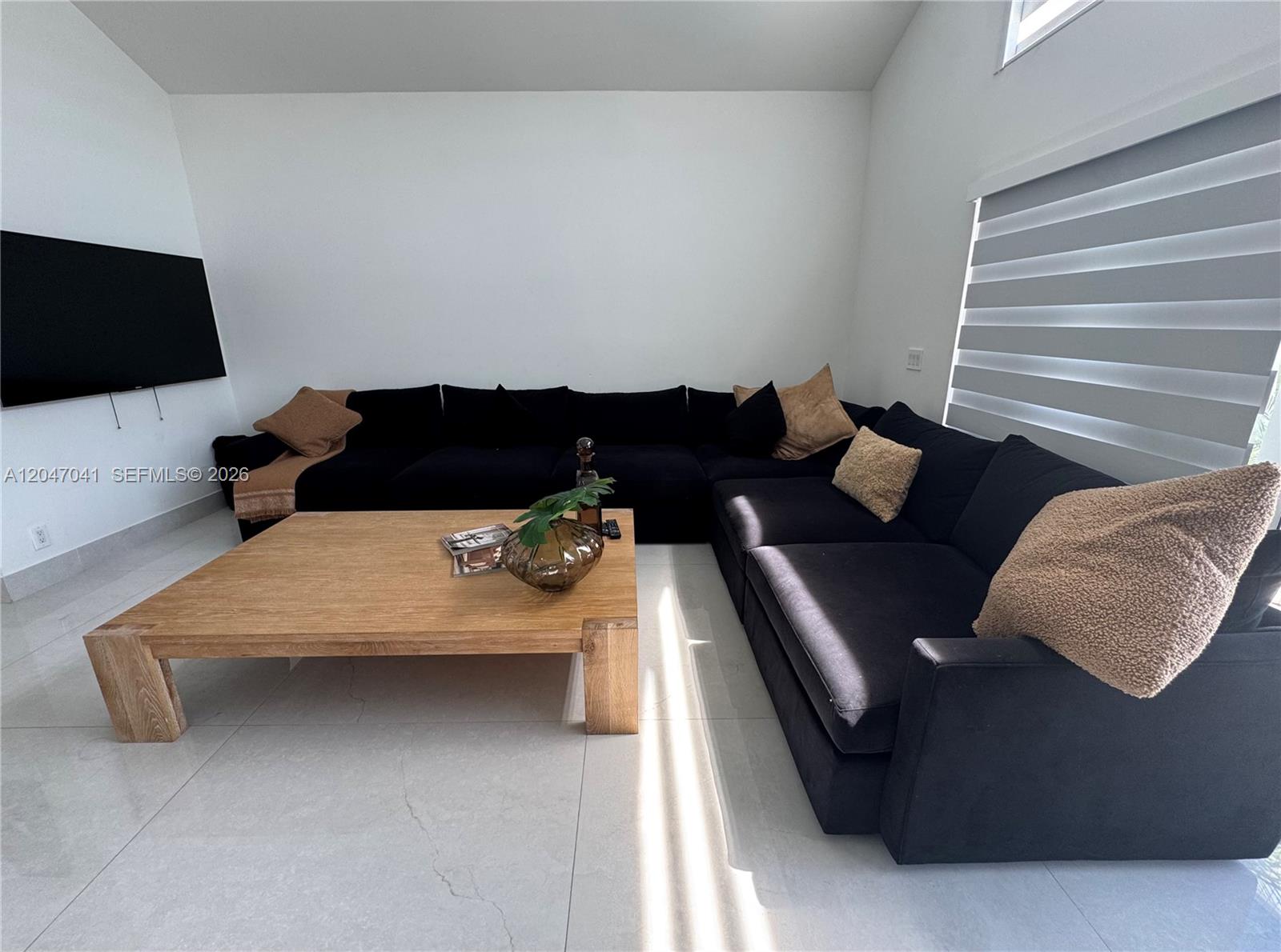 A living room features a large black sectional sofa, a light wood coffee table, and tile flooring — 4943 SW 33rd Way, Hollywood FL 33312, HOLLYWOOD, FL