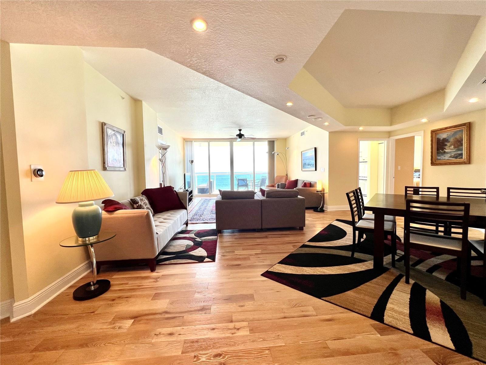 An open-concept living and dining area features hardwood floors, neutral walls, and ocean views — 6001 N Ocean Drive # 706, Hollywood FL 33019, HOLLYWOOD, FL
