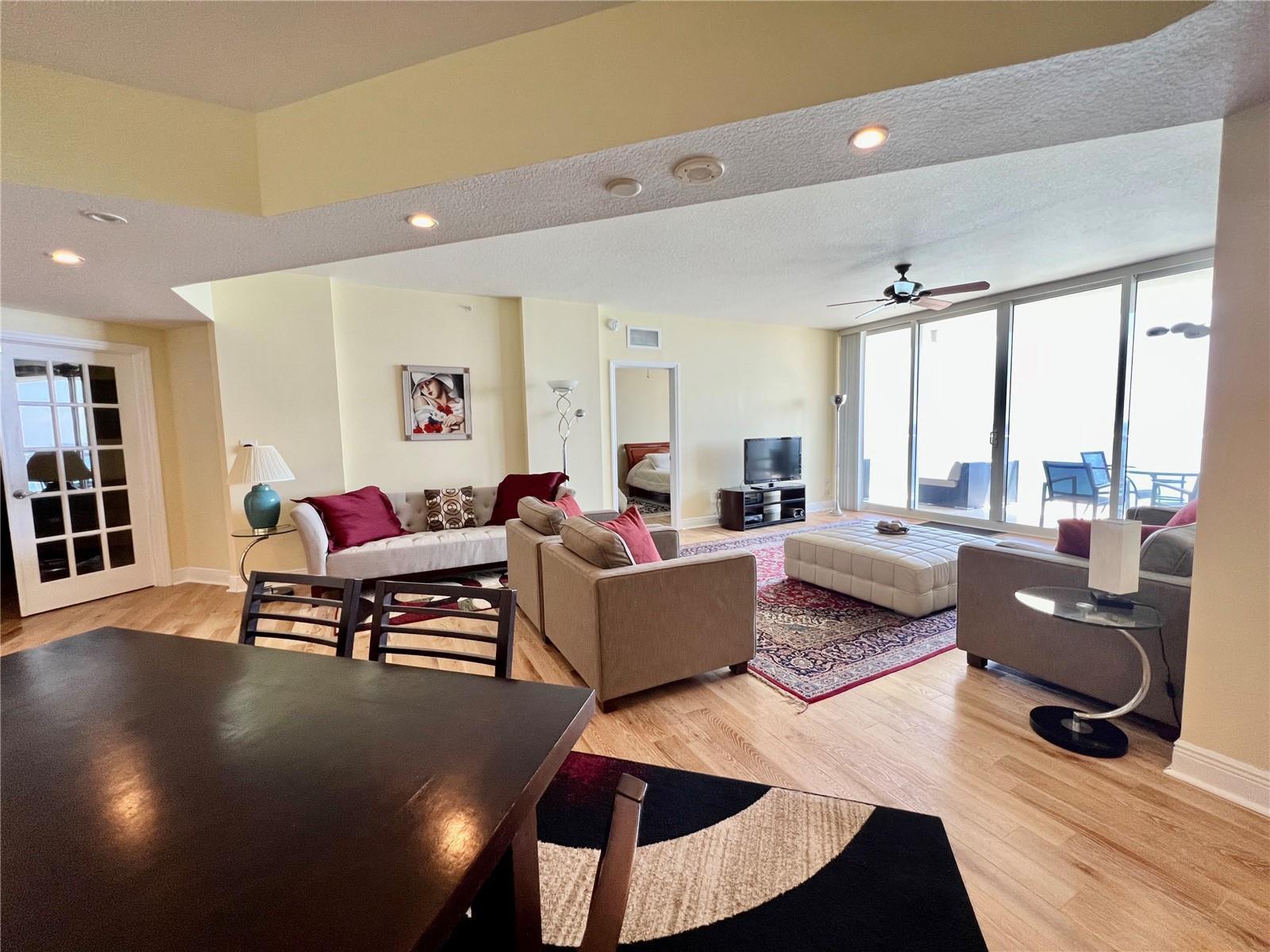 A living room with light wood floors, a large area rug, and floor-to-ceiling windows — 6001 N Ocean Drive # 706, Hollywood FL 33019, HOLLYWOOD, FL