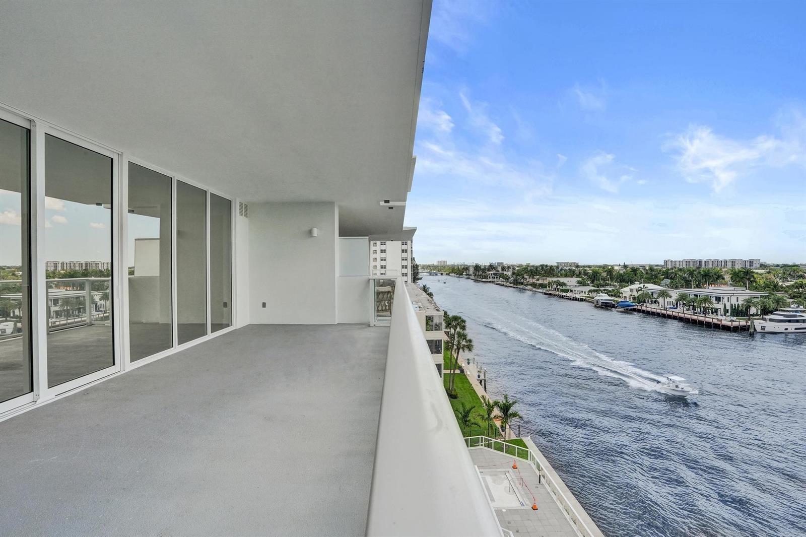 A high-rise balcony overlooks a canal with a boat moving through the water — 407 N Riverside Drive # 602, Pompano Beach FL 33062, POMPANO BEACH, FL
