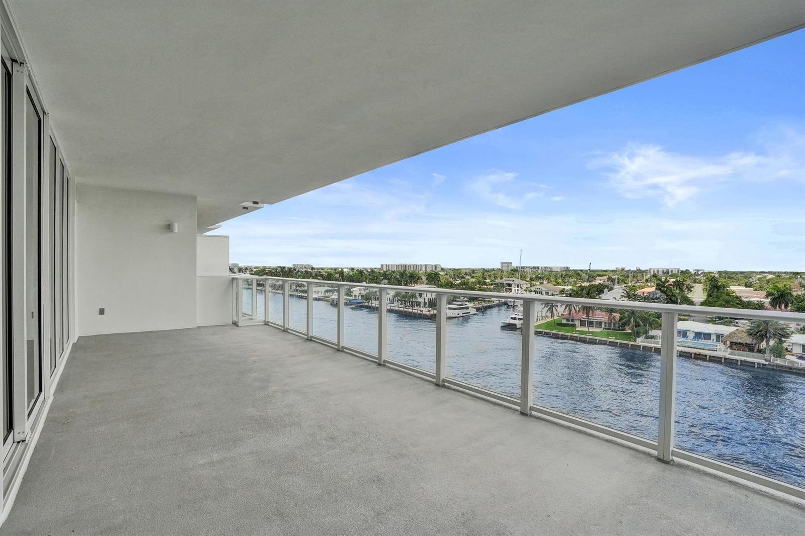 A wide, covered concrete balcony with a glass railing overlooks a canal and residential neighborhood — 407 N Riverside Drive # 602, Pompano Beach FL 33062, POMPANO BEACH, FL