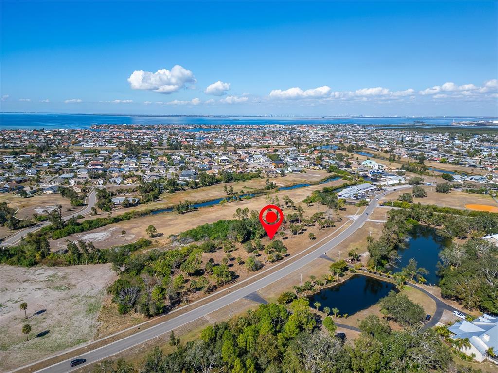 An aerial view shows a vacant, tree-dotted lot marked by a red pin near roads — 819 GOLF AND SEA BOULEVARD, APOLLO BEACH, FL