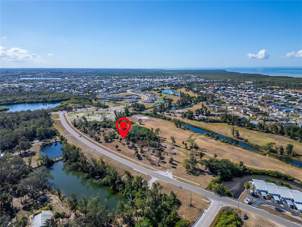An aerial view shows a vacant, tree-filled lot marked by a red pin near water — 819 GOLF AND SEA BOULEVARD, APOLLO BEACH, FL