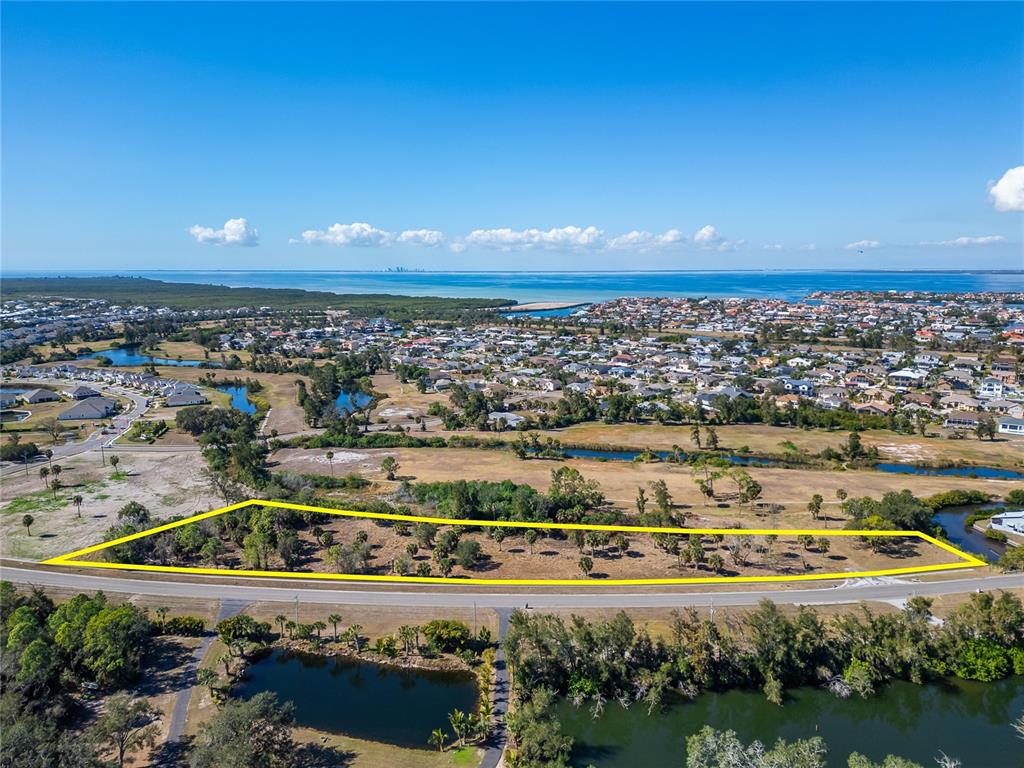 An aerial view shows a vacant, trapezoidal lot outlined in yellow next to a road — 819 GOLF AND SEA BOULEVARD, APOLLO BEACH, FL