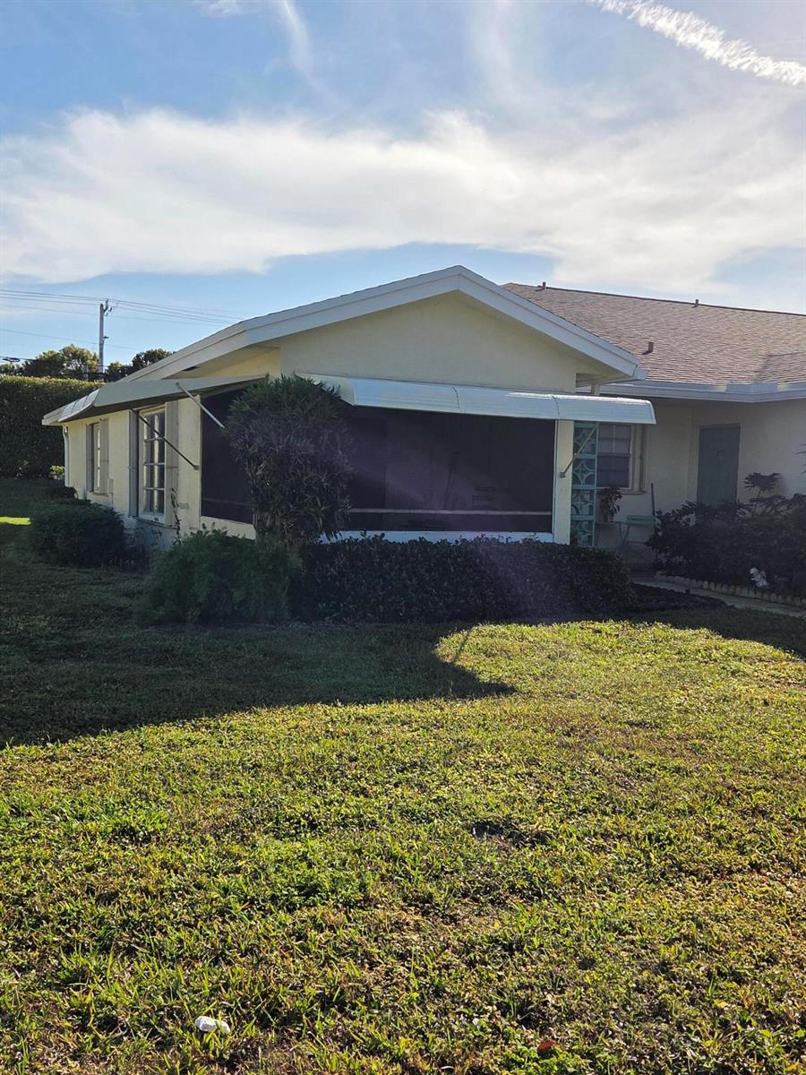 A yellow house features a screened-in porch with white metal awnings and a grassy yard — 5042 Lakefront Boulevard # A, Delray Beach FL 33484, DELRAY BEACH, FL