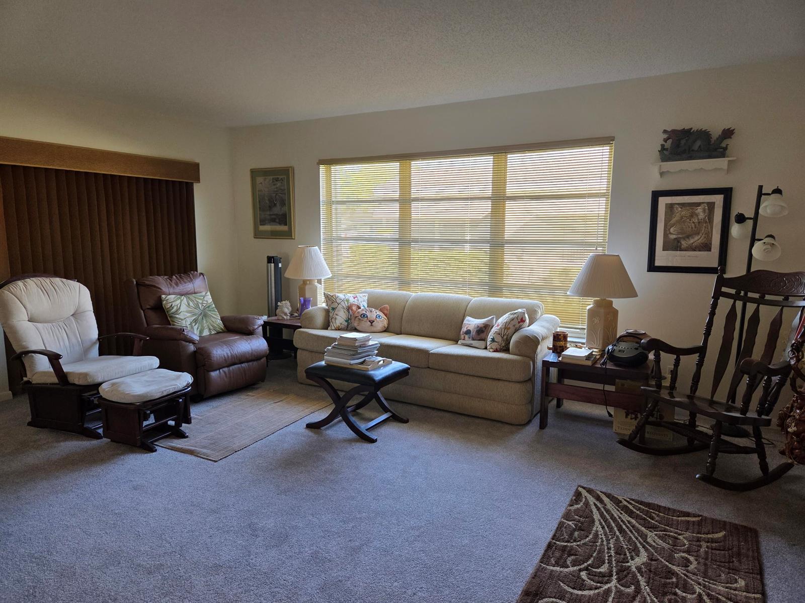 A living room features a beige sofa, a brown recliner, a rocking chair, and large windows — 5042 Lakefront Boulevard # A, Delray Beach FL 33484, DELRAY BEACH, FL