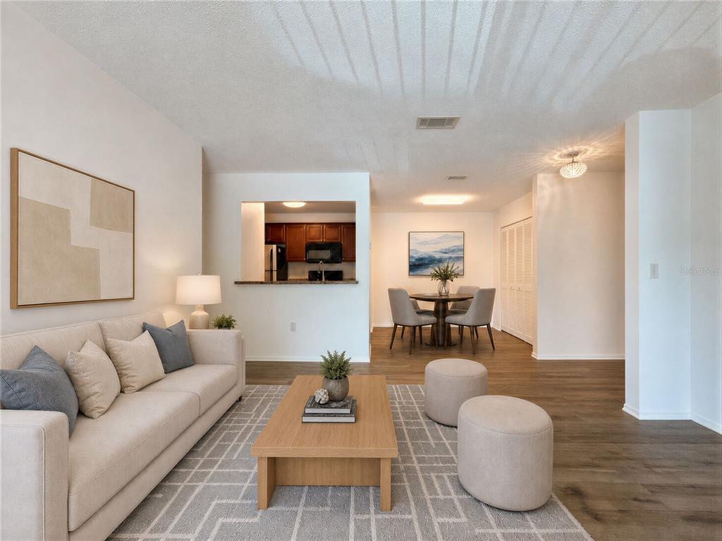 A living room with a beige sofa, wood coffee table, and an adjacent dining area — 3705 SW 27TH STREET UNIT 1225, GAINESVILLE, FL