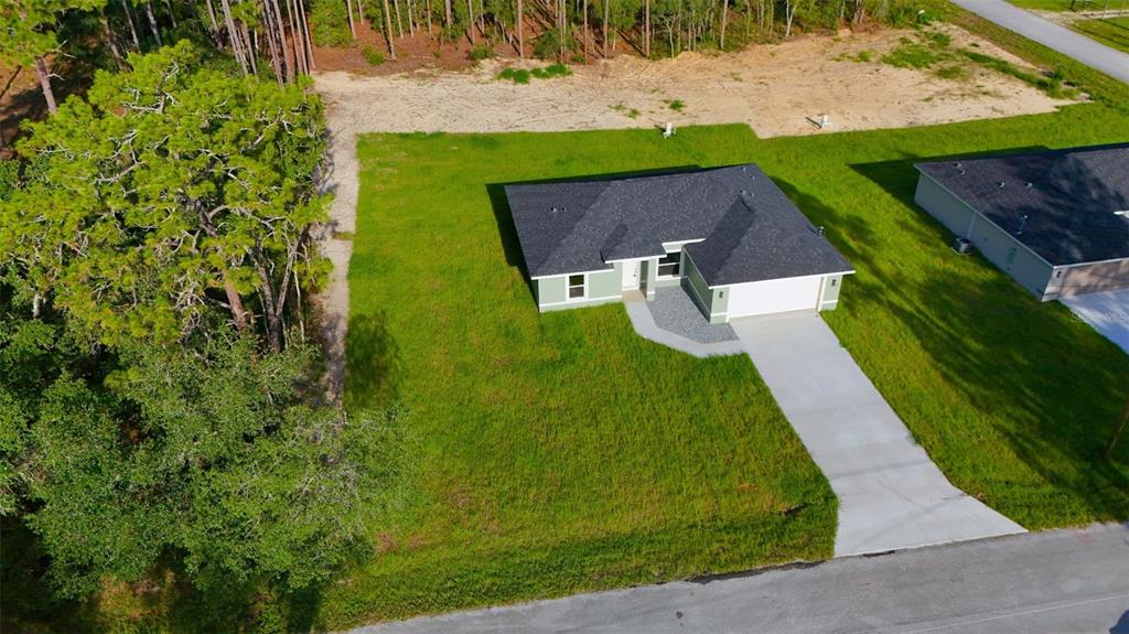An aerial view shows a single-story house with a green exterior, dark roof, and driveway — 6022 SW 206TH AVENUE, DUNNELLON, FL