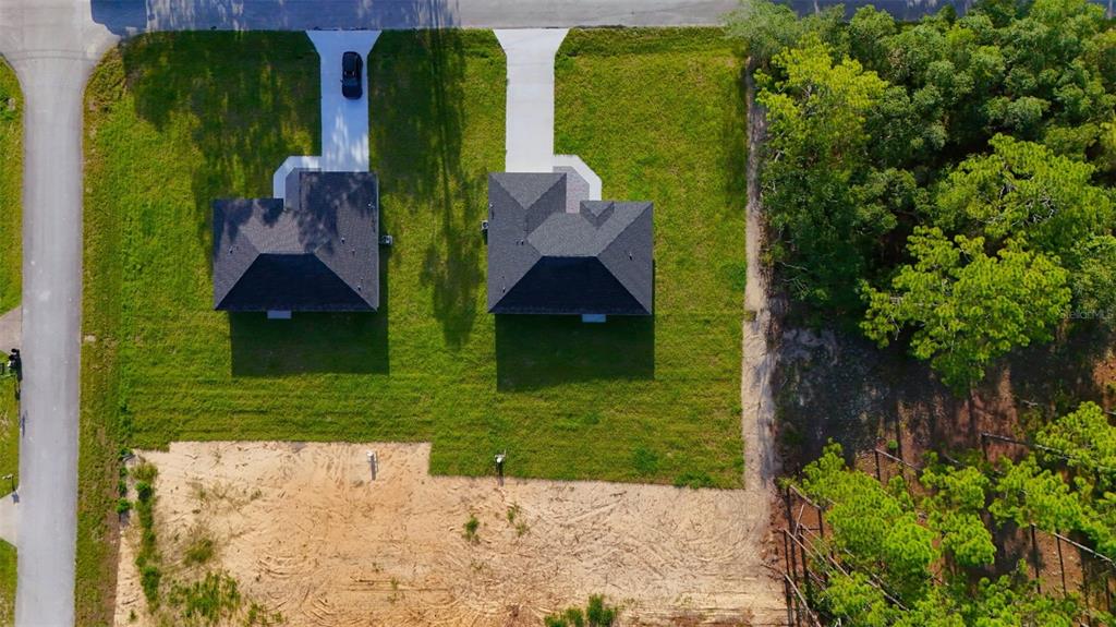 An aerial view shows two newly constructed houses with driveways situated on a grassy lot — 6022 SW 206TH AVENUE, DUNNELLON, FL