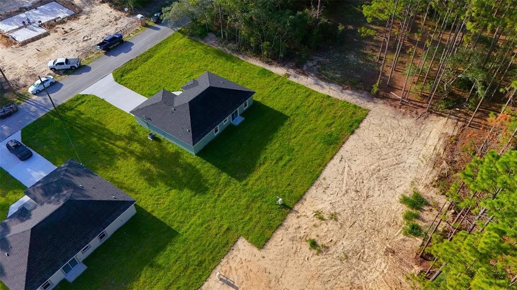 An aerial view shows two houses with dark roofs, green lawns, and adjacent wooded lots — 6022 SW 206TH AVENUE, DUNNELLON, FL