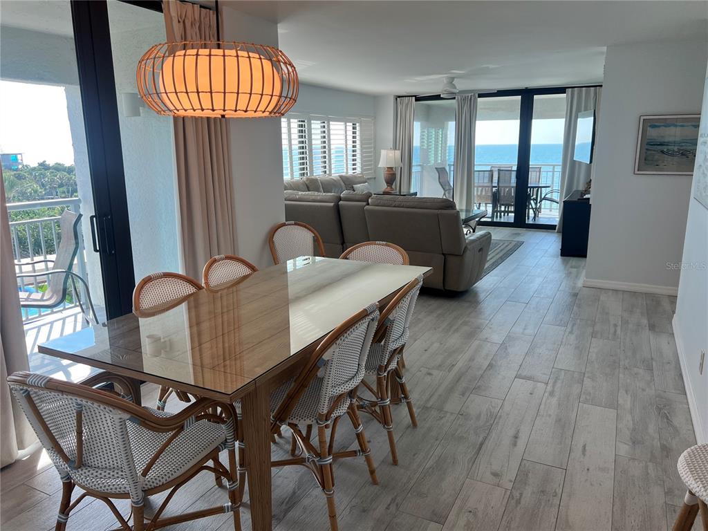 A dining area with a glass-topped table and wicker chairs overlooks a living room and balcony — 1001 POINT OF ROCKS ROAD UNIT 611, SARASOTA, FL