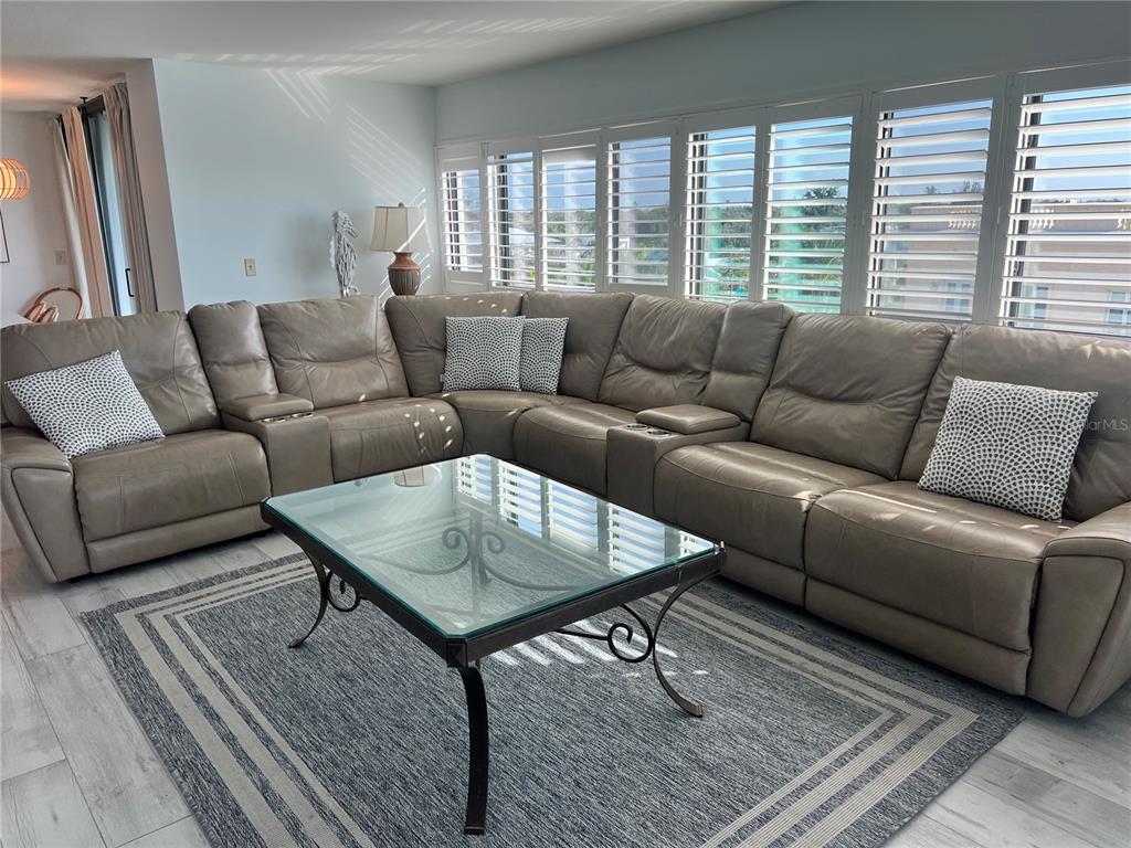 A living room features a large leather sectional sofa, a glass coffee table, and shutters — 1001 POINT OF ROCKS ROAD UNIT 611, SARASOTA, FL