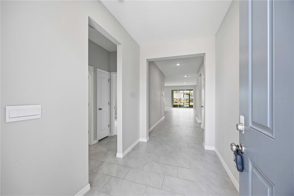 A view from an open front door into a tiled hallway leading to a living area — 5719 WOODLAND SAGE DRIVE, SARASOTA, FL