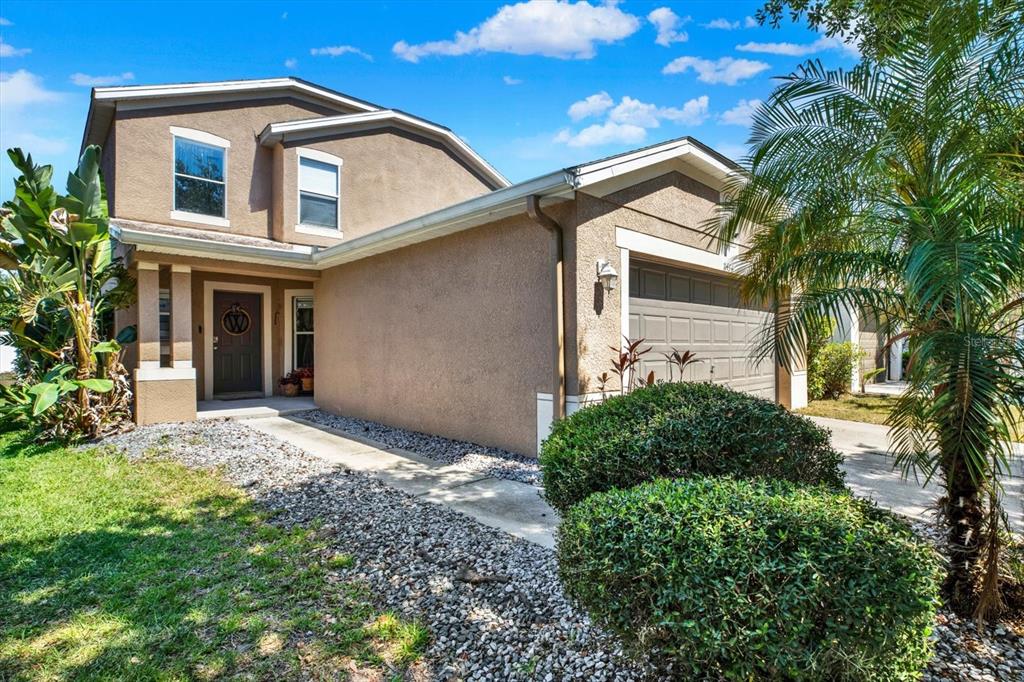A two-story stucco house with a garage, a front walkway, and landscaping under a blue sky — 11434 CRESTLAKE VILLAGE DRIVE, RIVERVIEW, FL